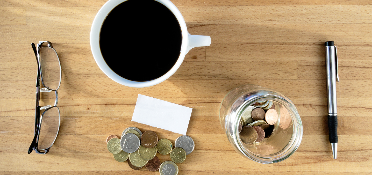 desk with coins, pen and coffee